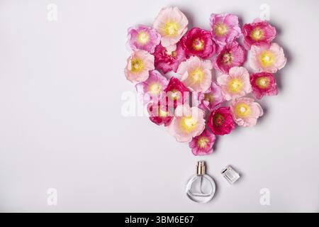 Le donne della bottiglia di profumo e di rosa fiori di malva. Il minimalismo Il concetto di bellezza Foto Stock
