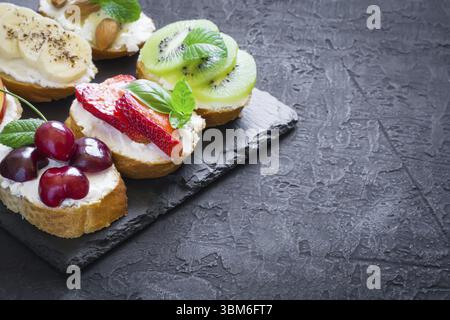 Estate assortiti snack dolci. La bruschetta o panini con frutti e bacche. spazio copia Foto Stock