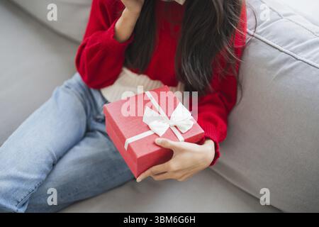 Ricevo il regalo di San Valentino. Allegra ragazza asiatica che tiene in custodia un regalo Foto Stock