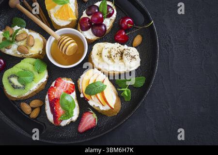 Estate assortiti snack dolci. La bruschetta o panini con frutti e bacche. Vista da sopra con lo spazio di copia Foto Stock