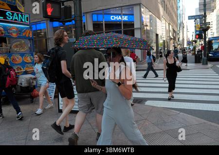 New York, Stati Uniti. 24 giugno 2025. Una persona cammina lungo la Fifth Avenue tenendo in mano un ombrello per bloccare la luce del sole durante un'ondata di caldo estivo a Manhattan, New York City. I newyorkesi stanno sperimentando alte temperature oltre i 90 gradi Fahrenheit e clima umido. Gli avvisi meteorologici invitano le persone a rimanere fresche e idratate. (Foto di Jimin Kim/SOPA Images/Sipa USA) credito: SIPA USA/Alamy Live News Foto Stock