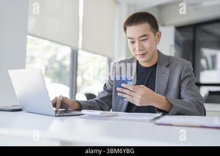 Uomo d'affari asiatico che lavora con un portatile. Giovane uomo d'affari che pensa concentrato sul lavoro Foto Stock