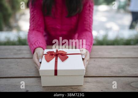 Felice eccitata donna asiatica mani che tengono in mano la confezione regalo di Natale. Allegra ragazza che prepara un regalo di Natale o un regalo di compleanno di Natale Foto Stock