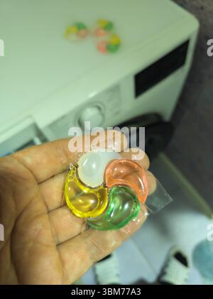 Uomo adulto in possesso di una cialda di detersivo per bucato in bagno la notte Foto Stock