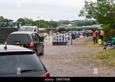 Pilton, Somerset, Regno Unito. 25 giugno 2025. Gli amanti del festival in auto che guidano al Glastonbury Festival a Pilton nel Somerset sono diretti in uno dei numerosi parcheggi prima che i cancelli aprano alle 8:00 in una calda mattinata ricoperta. Crediti fotografici: Graham Hunt/Alamy Live News Foto Stock