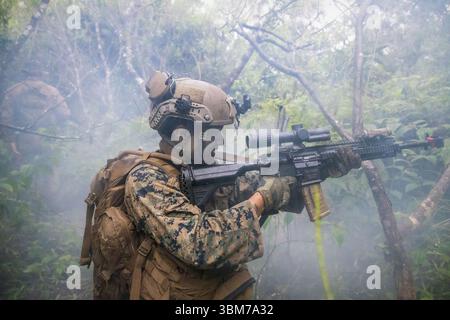 Bryan Anguianoruiz, fuciliere di fanteria di Long Beach, California, con la School of Infantry-West, Advanced Infantry Training Battalion, Detachment Hawaii, Advanced Infantry Marine Course (AIMC) classe 3-25, risponde a un'imboscata durante l'AIMC presso Kahuku Training area, Hawaii, 12 giugno 2025. Gli studenti dell'AIMC impararono e perfezionarono la trincea difensiva, le manovre offensive e il pattugliamento in ambienti austeri. (Foto del corpo dei Marines degli Stati Uniti di Lance Cpl. Samuel Estridge) Foto Stock