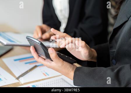 Analisi dei dati e collaborazione. Professionisti che utilizzano smartphone e documenti per l'analisi finanziaria. Foto Stock