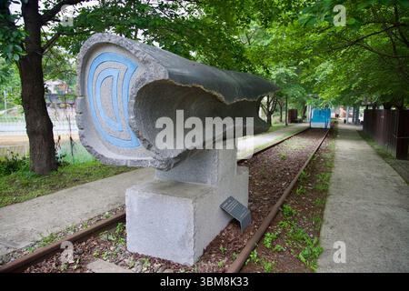 Contea di Yangpyeong, Corea del Sud - 19 maggio 2025: Una scultura in pietra grezza con linee blu scolpite si trova lungo i binari in disuso fuori dalla Galleria ASIN Foto Stock