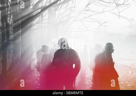 Soldato di fanteria tedesco della Wehrmacht nella seconda guerra mondiale in piedi in drammatica controluce attraverso fumo durante la rievocazione storica. Nero, rosso e bianco Foto Stock