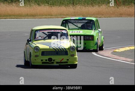 Due auto da corsa di colore verde brillante che sfrecciano in un angolo sul circuito Schleizer Dreieck in Germania. Veicolo classico della Germania dell'Est Foto Stock
