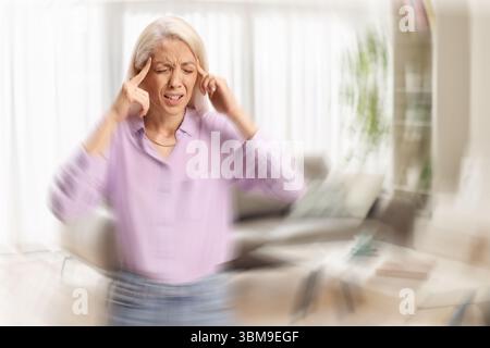 Giovane donna in piedi in salotto e si sente vertiginosa Foto Stock