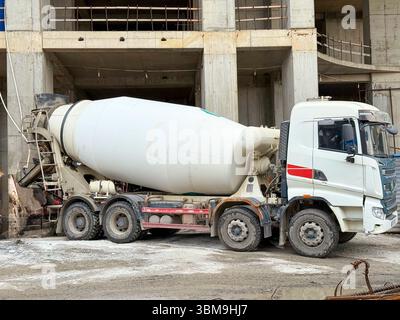 Carrello betoniera posizionato presso il cantiere con struttura parzialmente costruita Foto Stock