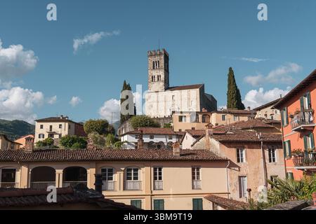 Vista panoramica degli edifici storici e della torre della chiesa a Barga, Toscana, Italia sotto il cielo blu. Foto di alta qualità Foto Stock