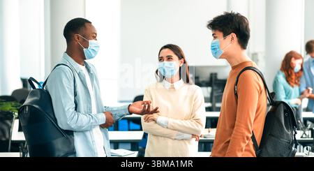 Studenti internazionali che indossano maschere mediche e parlano Foto Stock