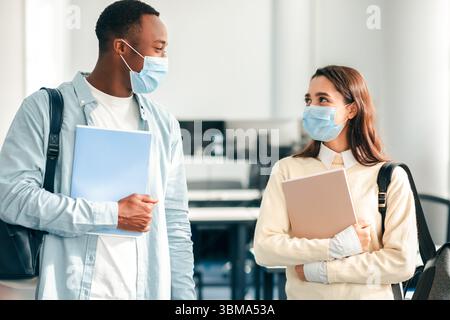 Studenti internazionali che indossano maschere mediche e parlano Foto Stock