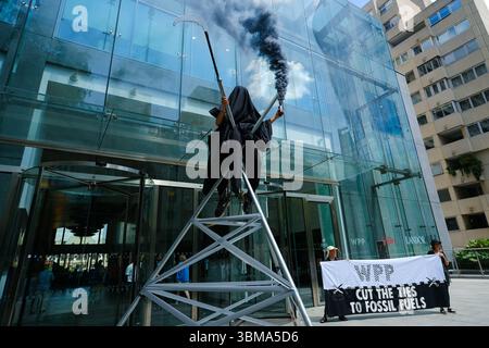 Londra, Regno Unito. 25 giugno 2025. Il gruppo di azione per il clima Extinction Rebellion porta l'ultima dimostrazione "Cut the Ties" agli uffici del gruppo di agenzie pubblicitarie WPP per incoraggiare le aziende di loro proprietà a smettere di lavorare con le società di combustibili fossili e a non accettare il lavoro di nuovi clienti, sostenendo che creano campagne progettate per indurre in errore. Gli attivisti si vestivano come il triste mietitore, i "lecchini del petrolio", e una gigantesca figura incombente di "morte" impegnata con i membri del pubblico, mentre altri occupavano la lobby dell'edificio. Credito: Fotografia dell'undicesima ora/Alamy Live News Foto Stock