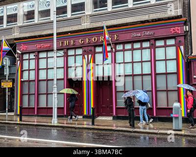 La facciata del George Pub con decorazioni arcobaleno e bandiere in una giornata di pioggia a Dublino, Irlanda. Una sede LGBTQ+ ben nota. Foto Stock
