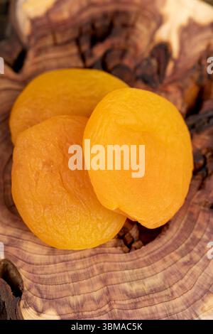 le albicocche secche snocciolate sono di colore giallo, molte albicocche secche vengono disidratate dopo aver rimosso i semi, le albicocche essiccate su un asse di legno, vie laterali Foto Stock