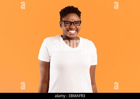 Positivo Plus-size Black Lady sorridente in piedi su sfondo giallo Foto Stock