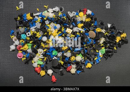 L'immagine mostra una raccolta di fermi e dispositivi di fissaggio universali per auto, comunemente noti come clip per paraurti o clip per rivestimenti Foto Stock