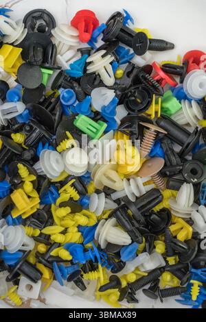 L'immagine mostra una raccolta di fermi e dispositivi di fissaggio universali per auto, comunemente noti come clip per paraurti o clip per rivestimenti Foto Stock