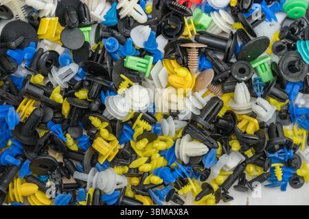 L'immagine mostra una raccolta di fermi e dispositivi di fissaggio universali per auto, comunemente noti come clip per paraurti o clip per rivestimenti Foto Stock