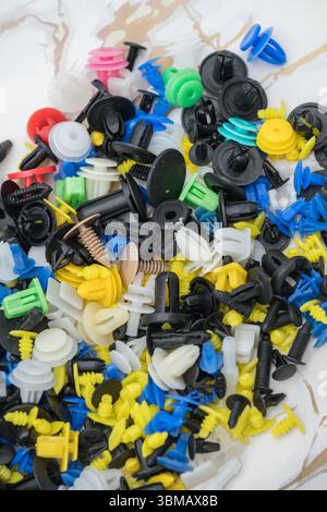 L'immagine mostra una raccolta di fermi e dispositivi di fissaggio universali per auto, comunemente noti come clip per paraurti o clip per rivestimenti Foto Stock