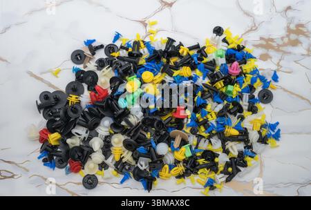 L'immagine mostra una raccolta di fermi e dispositivi di fissaggio universali per auto, comunemente noti come clip per paraurti o clip per rivestimenti Foto Stock