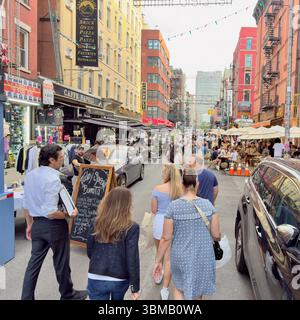 New York City, USA: 20 giugno 2025: Strada con ristoranti e folle di persone nel quartiere Little Italy, New York, USA Foto Stock