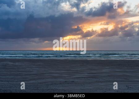 La luce del tramonto si rompe sotto le nuvole di tempesta sull'Atlantico a Maghera Beach, sabbia ondulata con bassa marea e surf dolce vicino ad Ardara, Contea di Donegal, Irlanda. Foto Stock