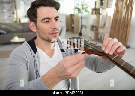 adulto artigiano che fissa la vecchia chitarra classica Foto Stock