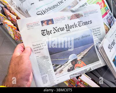 Parigi, Francia - 16 maggio 2025: A Person tiene l'edizione internazionale del New York Times presso un'edicola, la prima pagina contiene articoli sul nucleare Foto Stock