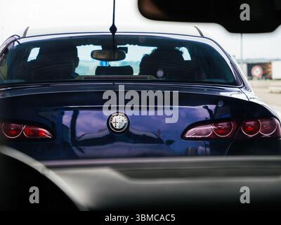 Boulogne, Francia - 24 agosto 2023: Vista ravvicinata di un veicolo Alfa Romeo visto attraverso il parabrezza di un'altra auto, con due persone visibili Foto Stock