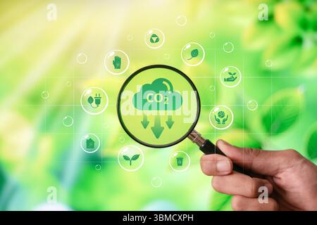 Una mano che regge una lente d'ingrandimento con un simbolo verde delle emissioni di CO2. Riduzione delle emissioni di CO2. Foto Stock