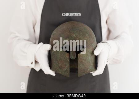 LONDRA, REGNO UNITO - 26 GIUGNO 2025: Un operatore artistico detiene un elmo corinzio greco in bronzo del periodo arcaico, tra la fine del vi e l'inizio del V secolo a.C., di forma iconica e provenienza impressionante, originariamente acquisito dalla Galerie Serres, Parigi, negli anni '1970, stima: £ 100.000 - 150.000 durante una chiamata fotografica alla casa d'aste Christie's prima di Antiquities sale a Londra, Regno Unito, il 26 giugno 2025. (Foto di Wiktor Szymanowicz/NurPhoto) Foto Stock