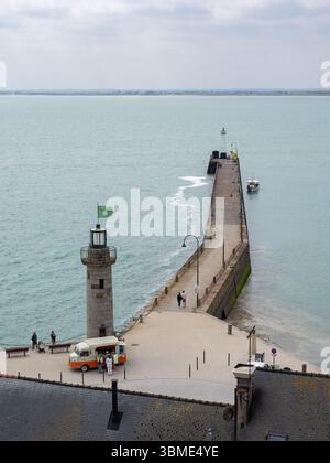 CANCALE, FRANCIA – 17 MAGGIO 2025: Veduta sopraelevata del faro di pietra e del molo di Cancale, Bretagna, con persone che camminano lungo il molo e un ristorante Foto Stock