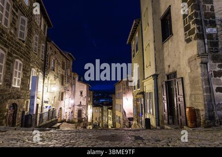 Ripida strada in discesa del centro storico di notte, illuminata da lanterne in vecchio stile. Le Puy-en-Velay, Francia. Foto Stock