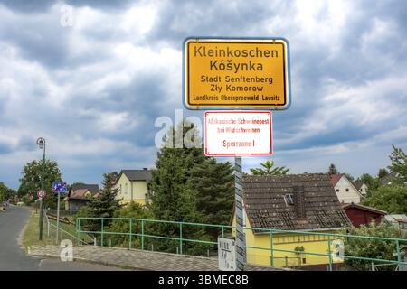 Cartello con il nome del luogo nel distretto Senftenberg di Kleinkoschen, basso Sorbian KoTynka, in tedesco e Sorbian, con riferimento alla peste suina africana in Foto Stock