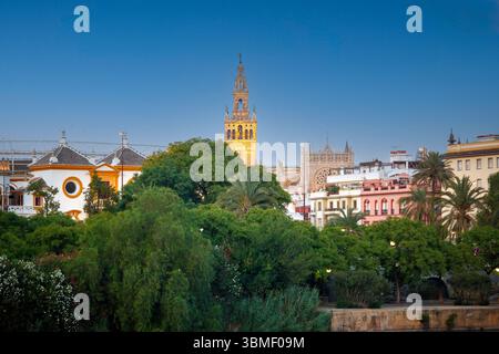 Gli scintillanti edifici di Siviglia si riflettono nel Guadalquivir mentre l'ora d'oro illumina la Giralda, la Cattedrale e l'arena. Foto Stock