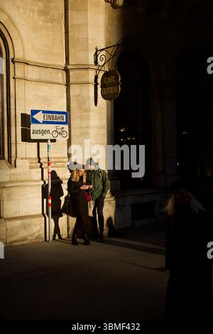 Giovane coppia che insegue gli ultimi raggi di sole in una strada fuori dal famoso Café Central di Vienna a febbraio. Foto Stock