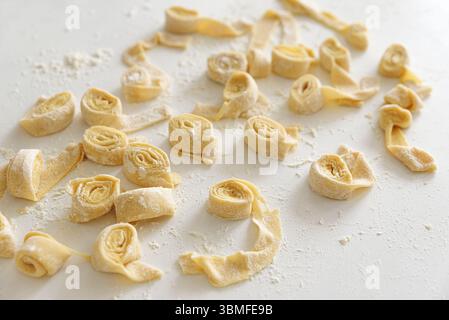 Pasta cruda appena preparata su una superficie bianca. Foto Stock