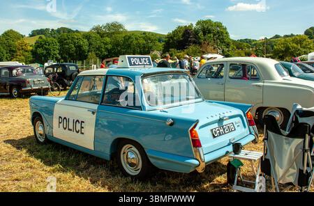 Auto della polizia Triumph Herald blu d'epoca esposta ad una mostra di auto d'epoca in una giornata di sole in un paesaggio rurale panoramico Foto Stock