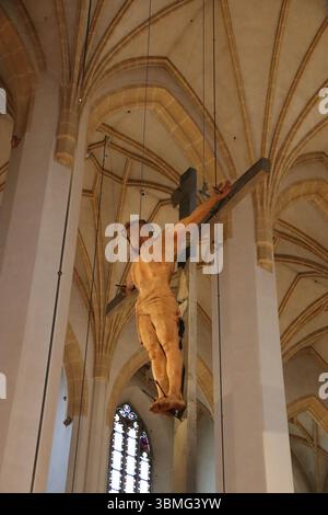 MONACO DI BAVIERA, GERMANIA - 24 GIUGNO 2025: Vista interna di Heilig-Geist-Kirche che mostra la scultura sospesa del crocifisso di Gesù Cristo contro le volte a costine Foto Stock