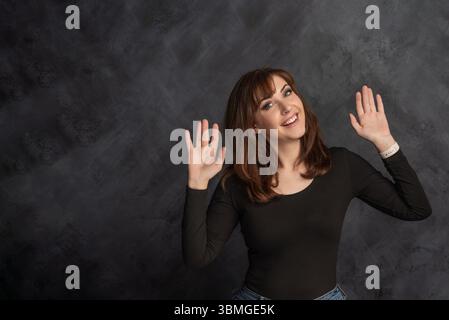 Donna felice in maglione nero con le braccia sollevate Foto Stock
