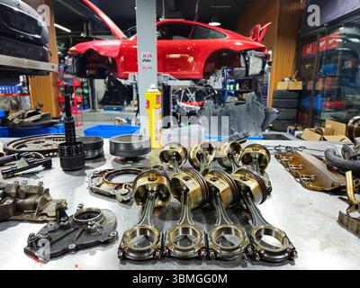 Porsche 911 sullo sfondo di pistoni e componenti del motore smontati Foto Stock