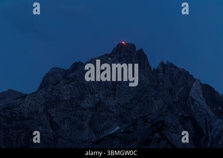 Lermoos, Austria. 21 giugno 2025. Il fuoco rosso può essere visto sul 21.06.2025 vicino alla croce sommitale dell'Ehrwalder Sonnenspitze nella Mieminger Kette vicino a Ehrwald in Tirolo (Austria). Crediti: Matthias Balk/dpa/Alamy Live News Foto Stock