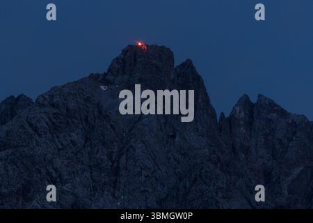 Lermoos, Austria. 21 giugno 2025. Il fuoco rosso può essere visto sul 21.06.2025 vicino alla croce sommitale dell'Ehrwalder Sonnenspitze nella Mieminger Kette vicino a Ehrwald in Tirolo (Austria). Crediti: Matthias Balk/dpa/Alamy Live News Foto Stock