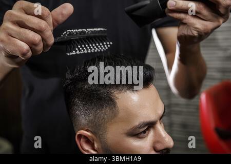 Taglio di capelli ravvicinati di un ragazzo dai capelli scuri. fotografia cinematografica Foto Stock