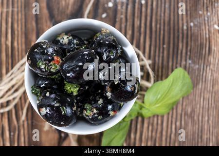 Porzione di decapare le olive nere con aglio ed erbe fresche (close-up shot) Foto Stock