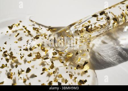 Pipetta e goccia di prodotto cosmetico con particelle d'oro, messa a fuoco selettiva Foto Stock